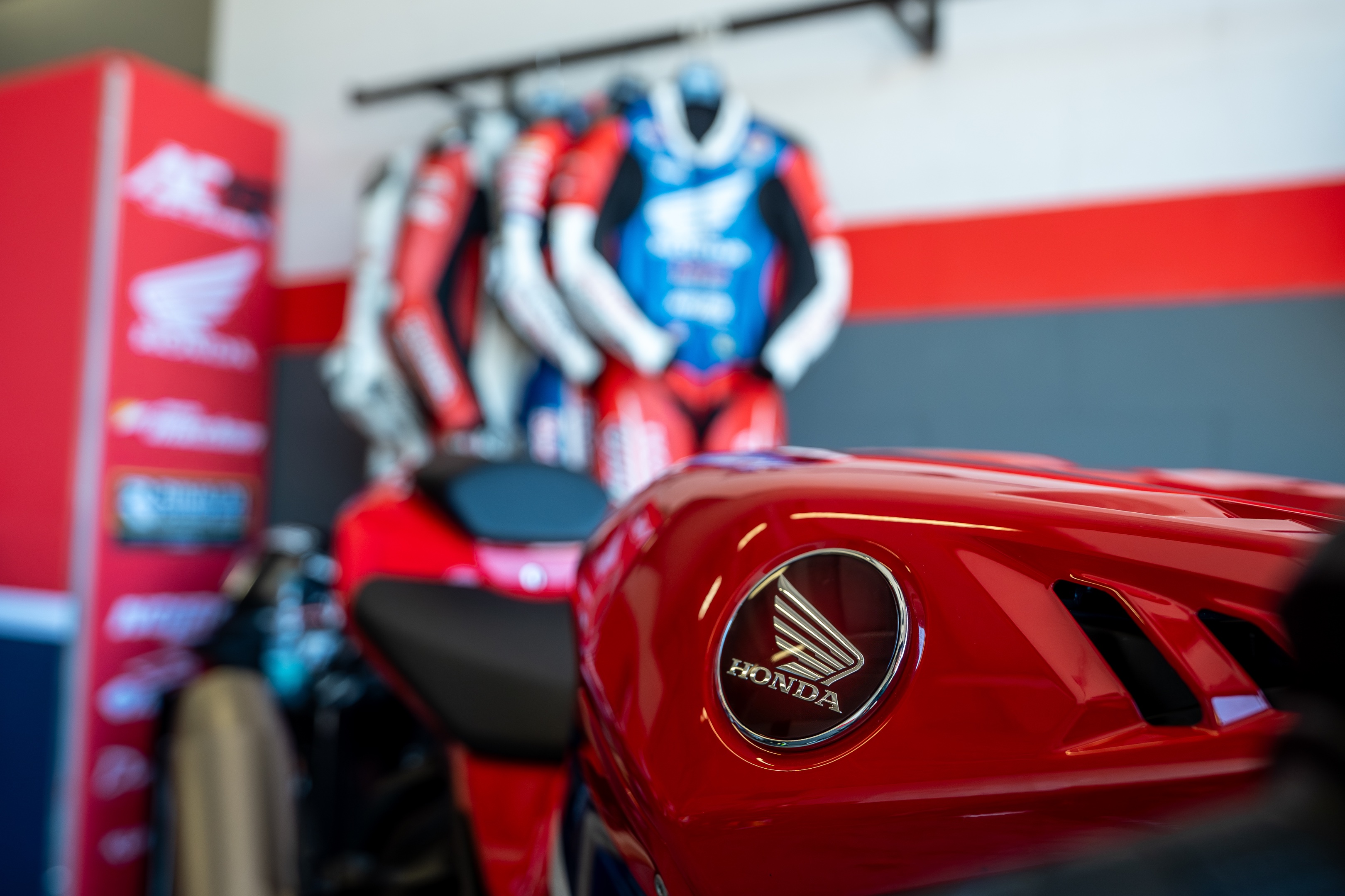 Moto Honda rossa e tute racing nel paddock AC19 Safe School